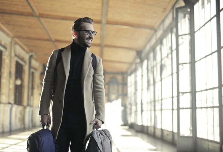 The Essentials of Blogging: Tips and Strategies for Success Smiling man in a winter coat with bags walking through a bright train station corridor.